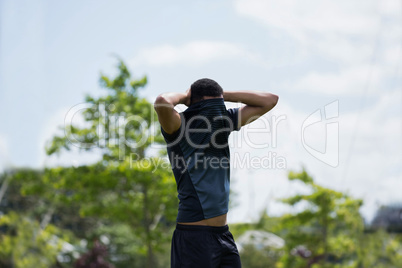 Soccer player standing with hand behind head