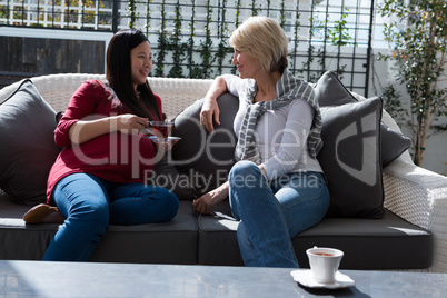 Female friends interacting with each other while having lemon tea