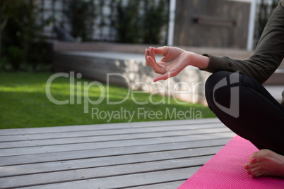 Mid section of woman practicing yoga in porch