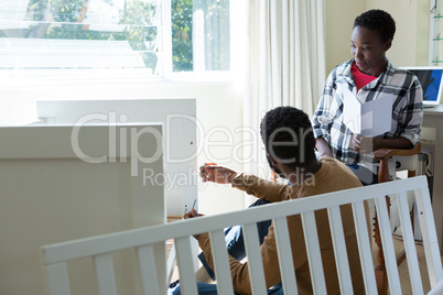 Man making cot with pregnant woman in bedroom