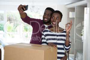 Couple showing house key while taking selfie with mobile phone