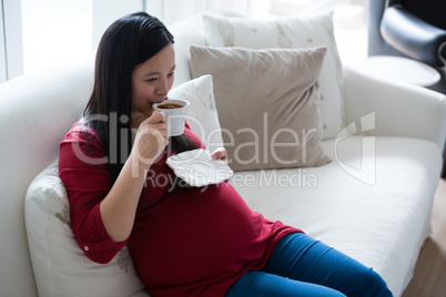 Pregnant woman having coffee in living room