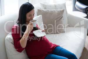 Pregnant woman having coffee in living room