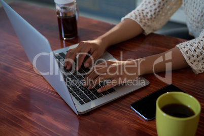 Mid section of woman using laptop at desk