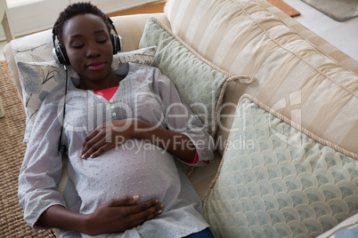 Pregnant woman listening music on headphones