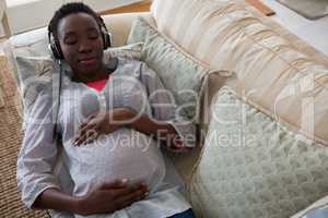 Pregnant woman listening music on headphones