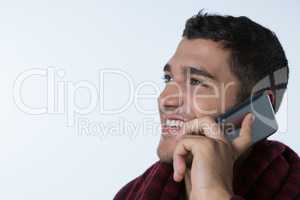 Smiling man talking on mobile phone against white background