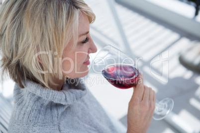 Beautiful woman smelling red wine in porch