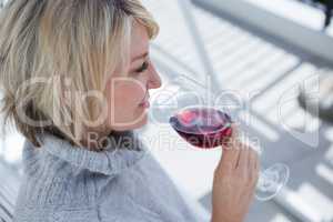 Beautiful woman smelling red wine in porch