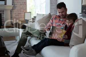 Father ans son reading book in living room