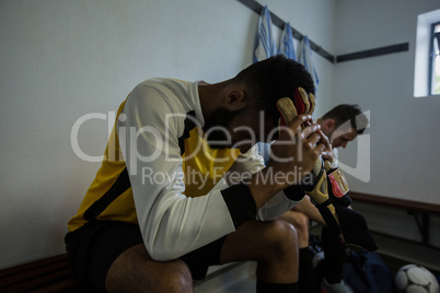 Football players sitting on bench in changing room