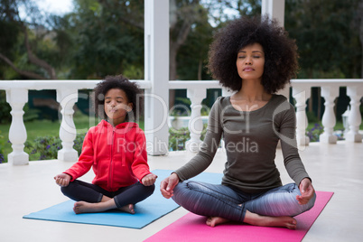 Mother and daughter meditating together in the porch