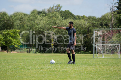 Football player standing with soccer in the ground