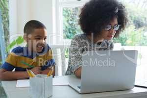 Son dosing homework while mother using laptop