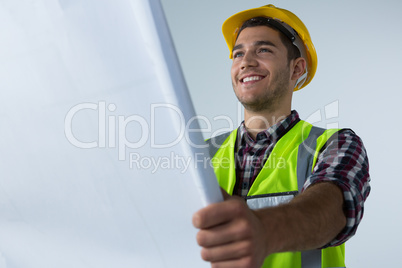 Male architect looking at blueprint against white background