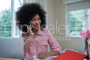 Beautiful woman talking on mobile phone at desk
