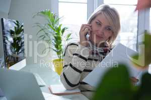 Beautiful woman discussing over document on mobile phone