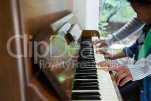 Mother assisting daughter in playing piano