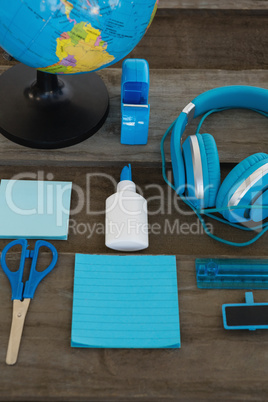 Headphone and globe with various stationery on wooden surface