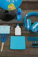 Headphone and globe with various stationery on wooden surface