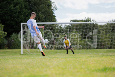 Soccer player kicking ball towards goal post
