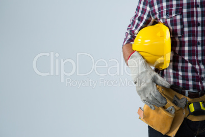 Architect with tool belt and holding hard hat against white background