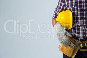 Architect with tool belt and holding hard hat against white background