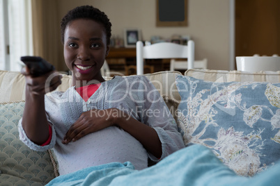 Pregnant woman watching television in living room