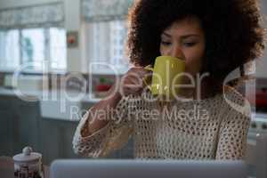 Beautiful woman having coffee while using laptop