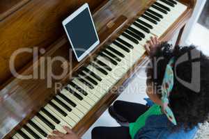 Girl playing piano with digital tablet