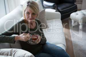 Thoughtful woman having lemon tea in living room