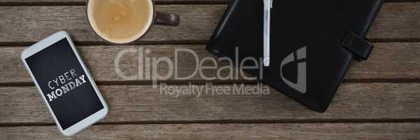 Composite image of mobile phone, coffee, pen and organizer on wooden plank