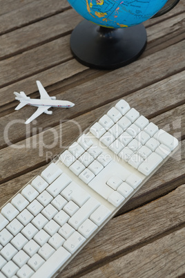 Globe, airplane model and keyboard on wooden plank