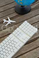 Globe, airplane model and keyboard on wooden plank