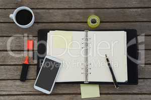 Black coffee, mobile phone and office supplies on wooden plank