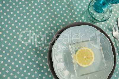 Sliced lemon in bowl with various cutlery on table cloth