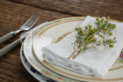 Fork and butter knife with napkin and flower arranged in a plate