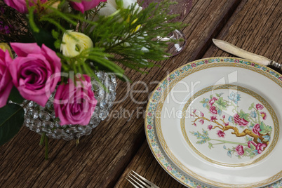 Fork and butter knife with plate arranged on wooden table