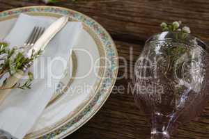Fork and butter knife with flower and napkin on wooden table