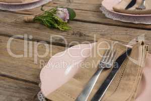 Plates with napkin, fork and butter knife arranged on wooden table