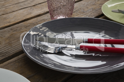 Plate with fork, butter knife and glass on wooden table