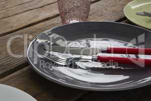 Plate with fork, butter knife and glass on wooden table