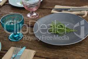 Plates with napkin, fork, butter knife and flower arranged on wooden table