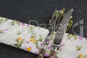 Fork and butter knife with flower and table cloth on black background