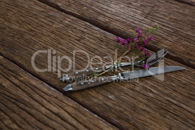 Fork and butter knife with flower on wooden table