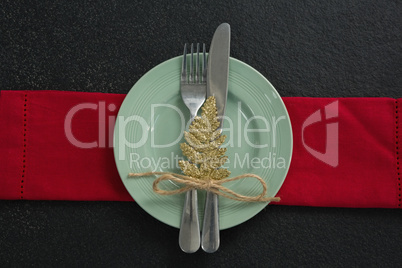 Christmas ornament, fork and knife in a plate with napkin