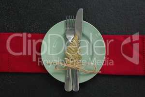Christmas ornament, fork and knife in a plate with napkin