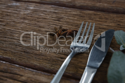 Fork with butter knife and star anise on wooden table