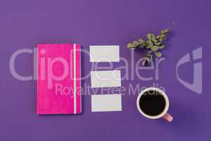 Dry leaves, file, visiting card and black coffee on purple background