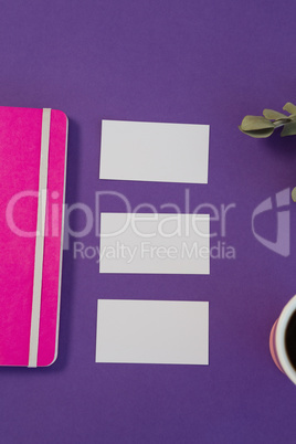 Dry leaves, file, visiting card and black coffee on purple background